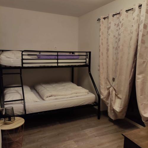 Cette chambre comprend 2 lits superposés et un rideau. dans l'établissement La Basse Biguerie proche zoo de la flèche, à Saint-Jean-de-la-Motte