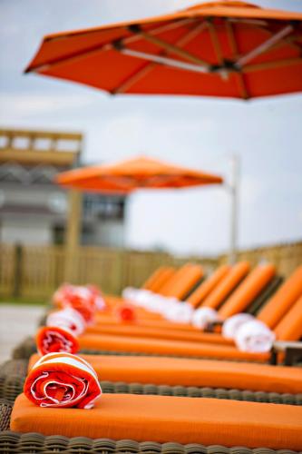 a row of orange chairs with a red umbrella at The Sanderling in Duck