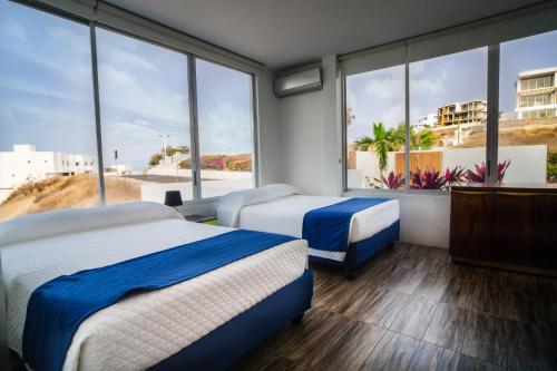 ein Hotelzimmer mit 2 Betten und großen Fenstern in der Unterkunft Exclusivo Penthouse frente al mar con acceso a la playa - Club Privado en Manta in Manta