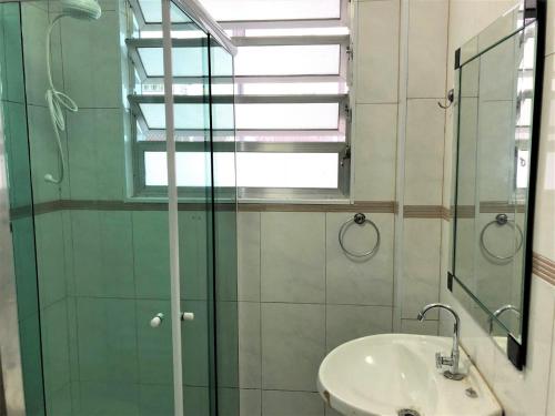 a bathroom with a sink and a glass shower at Apartamento em Praia Grande in Praia Grande
