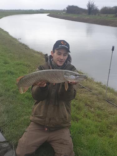 a man holding a fish in front of a lake at Morland in Burrowbridge