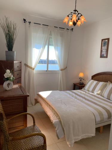1 dormitorio con 1 cama, 1 silla y 1 ventana en Apartment Attico, en Ayamonte