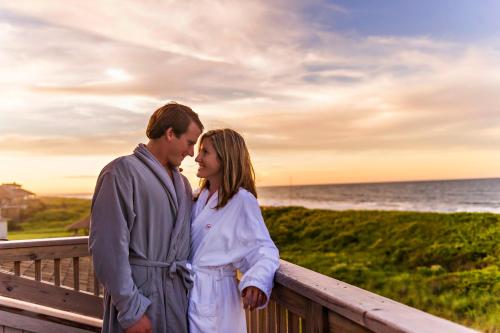 a man and a woman standing on a boardwalk near the ocean at The Sanderling in Duck