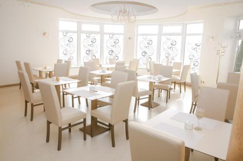 restauracja z białymi stołami, krzesłami i oknami w obiekcie Hotel Court Wellness&Spa w Kędzierzynie-Koźlu