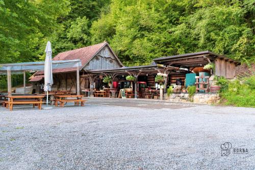 ein Gebäude mit Tischen, Stühlen und einem Regenschirm in der Unterkunft Kamp Jankovic in Gorenjcj