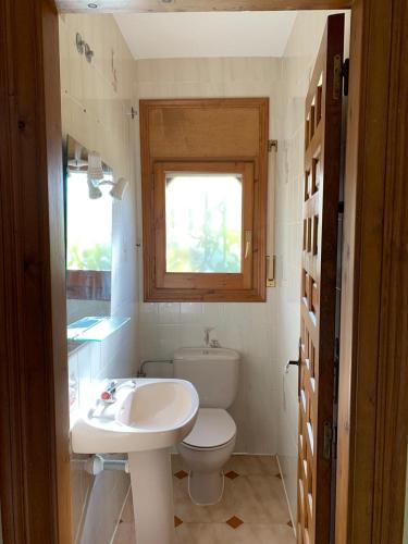 a bathroom with a toilet and a sink and a window at Villa Sonrisa de Oro - private swimming pool in Miami Platja