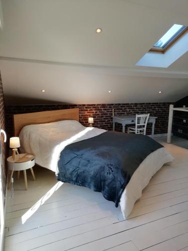 une chambre avec un grand lit et un mur de briques dans l'établissement La Maisonnette au cœur de la plaine, à LʼHôpital-le-Grand