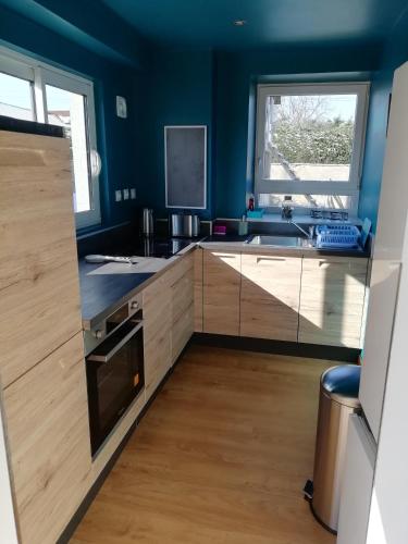 - une cuisine avec des murs bleus et des placards en bois dans l'établissement La Maisonnette au cœur de la plaine, à LʼHôpital-le-Grand