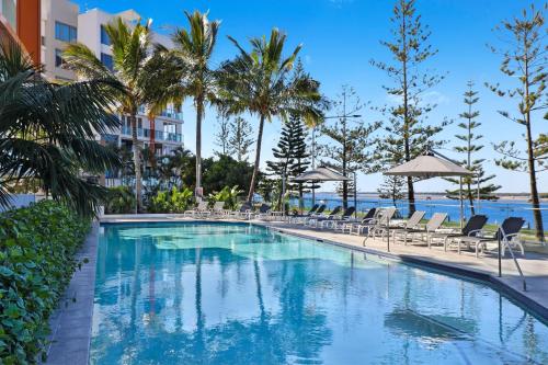 uma piscina num resort com cadeiras e palmeiras em Silvershore Apartments on the Broadwater em Gold Coast