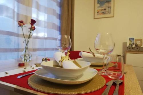 a table with two wine glasses and plates on it at Studio Cosy neuf proximité du Golf et de la Digue in Wimereux