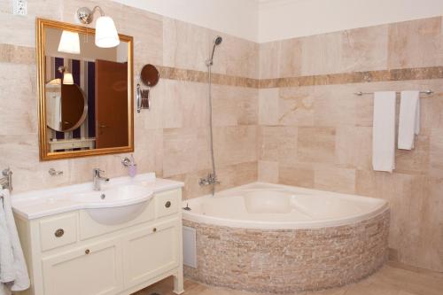 a bathroom with a tub and a sink and a mirror at Boutique Vila Paradis in Deva