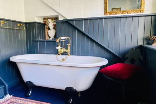 eine Badewanne in einem blauen Bad mit einem roten Kissen in der Unterkunft 17th Century Boutique Getaway in the Countryside in Martin