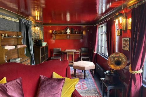 a red living room with a red couch and a table at 17th Century Boutique Getaway in the Countryside in Martin