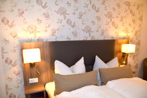 a bedroom with a bed with white pillows and floral wallpaper at Pension Lachmann in Pfaffendorf