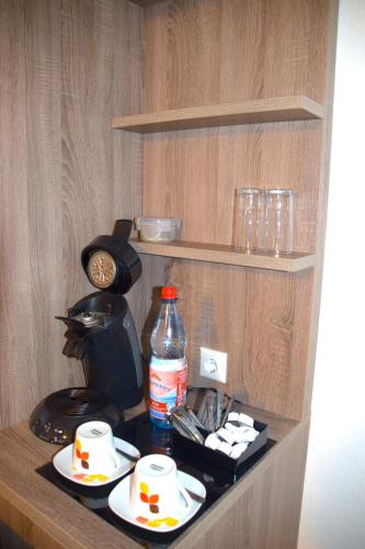 a shelf with cups and a bottle of water and a coffee maker at Pension Lachmann in Pfaffendorf