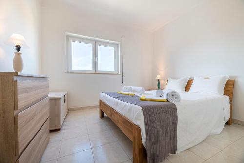 a bedroom with a bed and a dresser in a room at T2 Oásis Parque, Piscinas, Jacuzzi e ténis! in Portimão