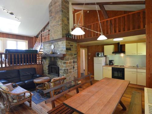 a living room with a table and a stone fireplace at Welcoming Cottage in Hatrival with Terrace in Saint-Hubert