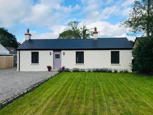 a white house with a green yard at Lavender Cottage - 2 Bedroom Home in Newbridge