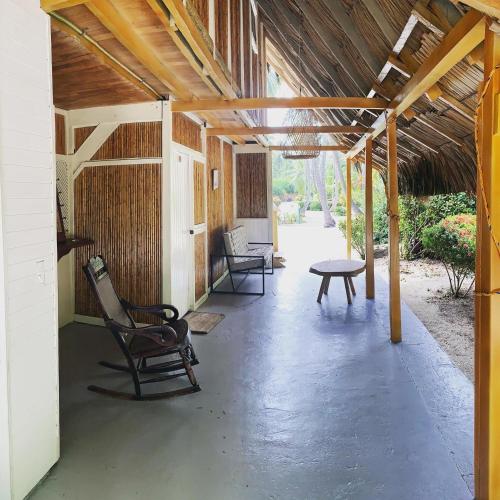 a covered porch with a table and chairs at Hotel Playa Bonita Tayrona in Buritaca