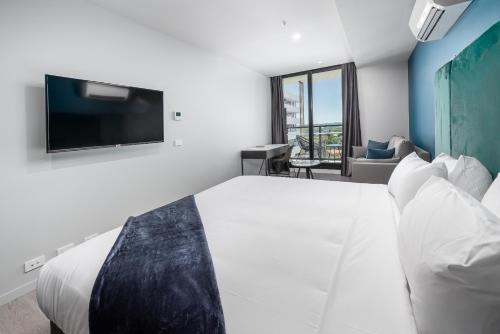a bedroom with a bed with a tv on the wall at Oros Hotel and Apartments in Oakleigh
