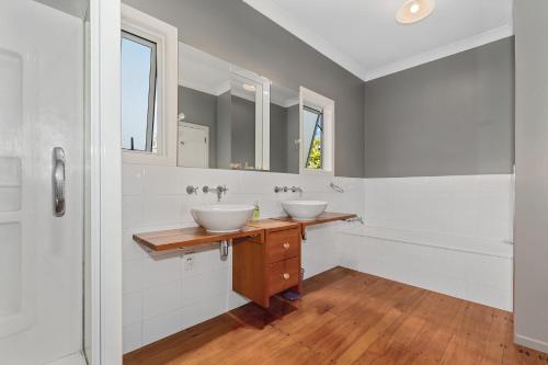 a bathroom with two sinks and two mirrors at Somerton - Waipu Holiday Home in Waipu Cove