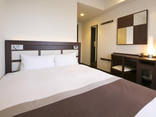 a hotel room with a bed and a desk at Urban Hotel Minami Kusatsu in Kusatsu