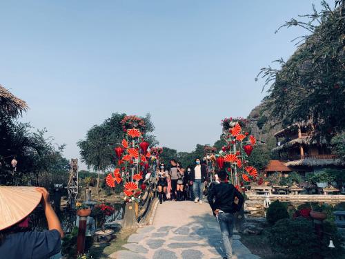 a group of people walking down a path with red flowers at Tuan Nam Homestay in Ninh Binh