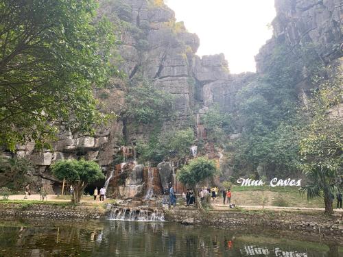 a group of people standing around a pond in front of a mountain at Tuan Nam Homestay in Ninh Binh