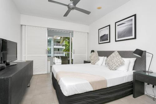Schlafzimmer mit einem großen Bett und einem Deckenventilator in der Unterkunft Seascape Holidays at The Beach Club in Port Douglas