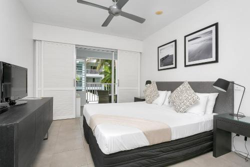 a bedroom with a large bed with a ceiling fan at Seascape Holidays at The Beach Club in Port Douglas