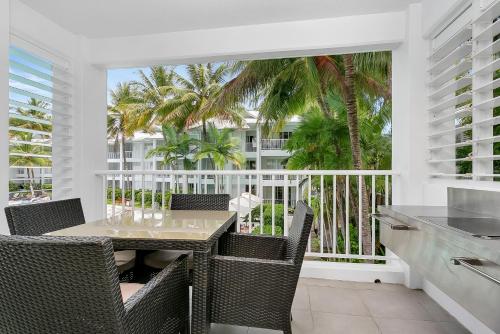 a dining room with a table and chairs on a balcony at Seascape Holidays at The Beach Club in Port Douglas
