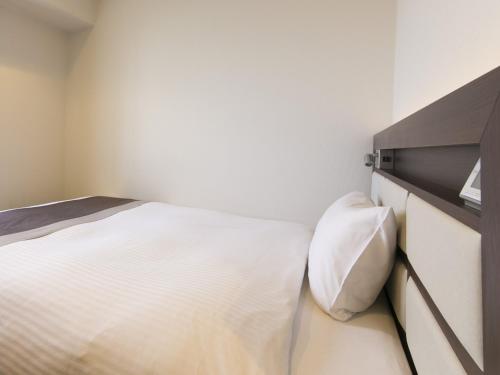 a bedroom with a white bed and a dresser at Urban Hotel Minami Kusatsu in Kusatsu