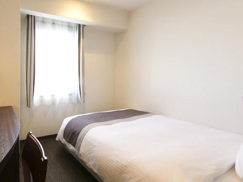 a white bedroom with a bed and a window at Urban Hotel Minami Kusatsu in Kusatsu
