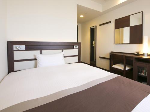 a bedroom with a large bed and a desk at Urban Hotel Minami Kusatsu in Kusatsu