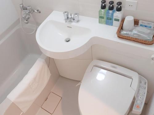 a white bathroom with a toilet and a sink at Urban Hotel Minami Kusatsu in Kusatsu