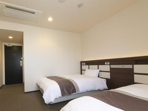 a hotel room with two beds and a window at Urban Hotel Minami Kusatsu in Kusatsu