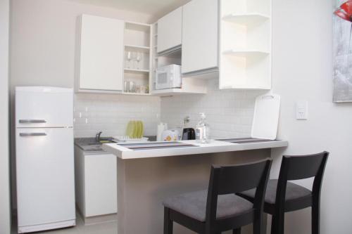 una cocina con armarios blancos y 2 sillas en un mostrador en Bonaire V apartamento 2 Personas a 1 cuadra de la costanera en Corrientes