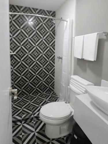 La salle de bains est pourvue de toilettes et d'un mur noir et blanc à motifs. dans l'établissement Casa moderna equipada como hotel Habitación 1, à Monterrey