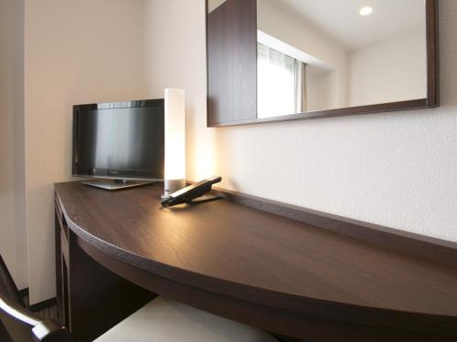 a room with a desk with a television and a mirror at Urban Hotel Minami Kusatsu in Kusatsu