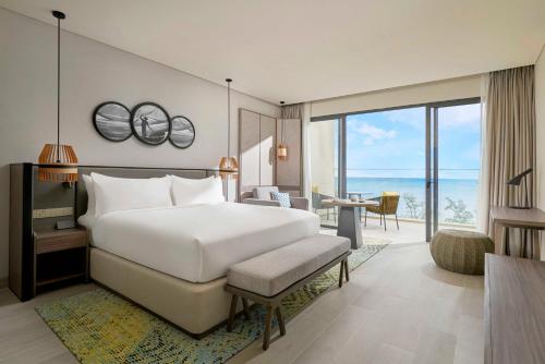 a bedroom with a large white bed and a living room at Crowne Plaza Phu Quoc Starbay by IHG in Phu Quoc