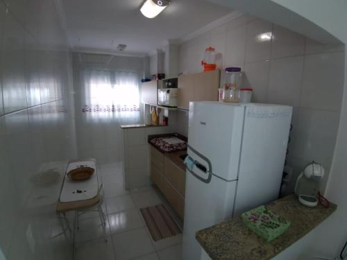a small kitchen with a white refrigerator and a table at Praia grande, aviação, apenas 180 mtrs do mar!!! in Praia Grande