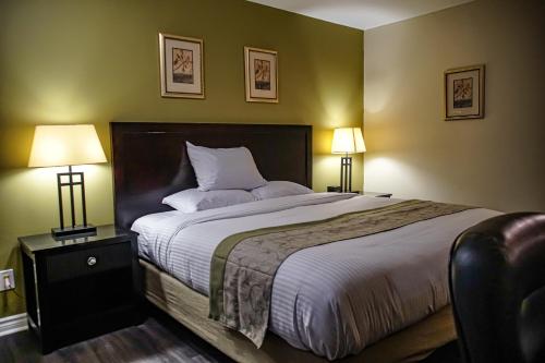 a bedroom with a large bed with two lamps at Skyland Motel Inn & Suites in Huntsville