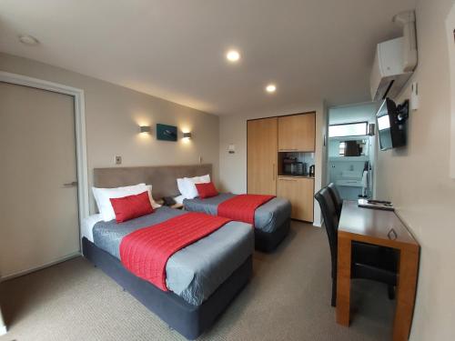 Habitación de hotel con 2 camas, escritorio y escritorio. en The Fairways Luxury Accommodation Kaikoura en Kaikoura