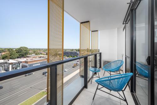 a balcony with blue chairs and a view of a highway at Oros Hotel and Apartments in Oakleigh