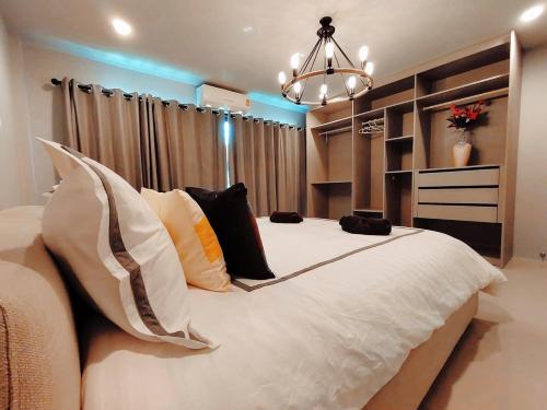 a bedroom with a large bed with pillows and a chandelier at The Nakara Town in Ban Rangeng