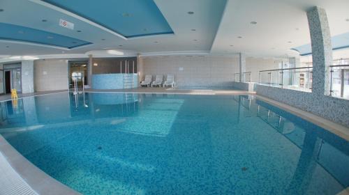 a large swimming pool with blue water in a building at Siófok Club 218 Wellness Apartman in Siófok