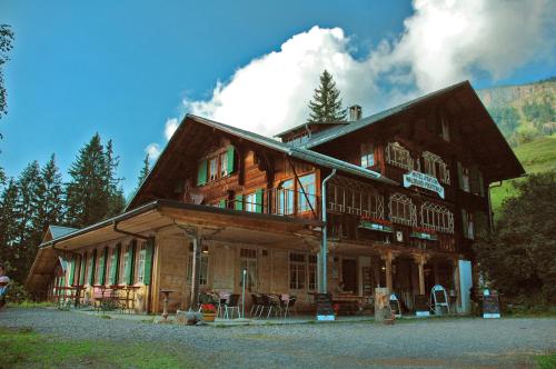 a large wooden house with a mountain in the background at Hotel Waldrand in Kiental