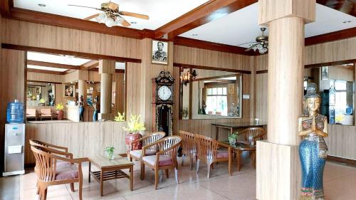 jadalnia ze stołem, krzesłami i zegarem w obiekcie Suriwong Chumphon Hotel w mieście Chumphon