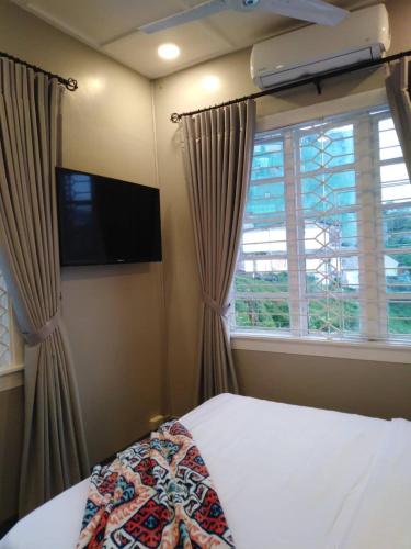 a bedroom with a bed and a tv and a window at R Bed and Breakfast in Baguio