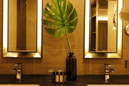 全州市にあるBest Western Plus Jeonjuの浴室のカウンターに植物を入れた黒い花瓶